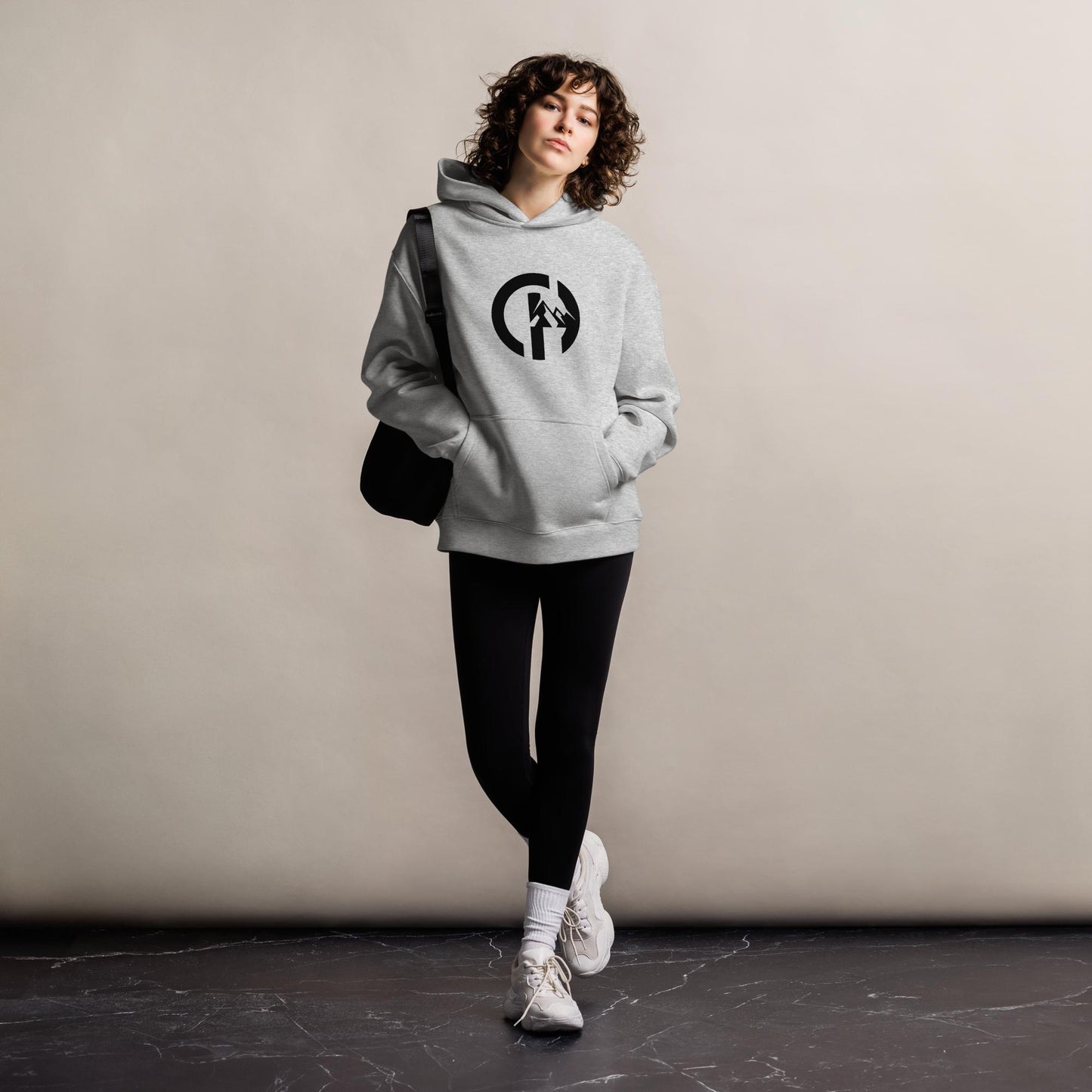 Chillhawk Unisex oversized hoodie in athletic heather - front view of a person with dark hair is standing and wearing a athletic heather, ultra-soft, heavyweight oversized hoodie with a relaxed fit. The hoodie has the "CHILLHAWK" logo on the chest. The hoodie is designed for comfort and style, suitable for both city streets and slopes.