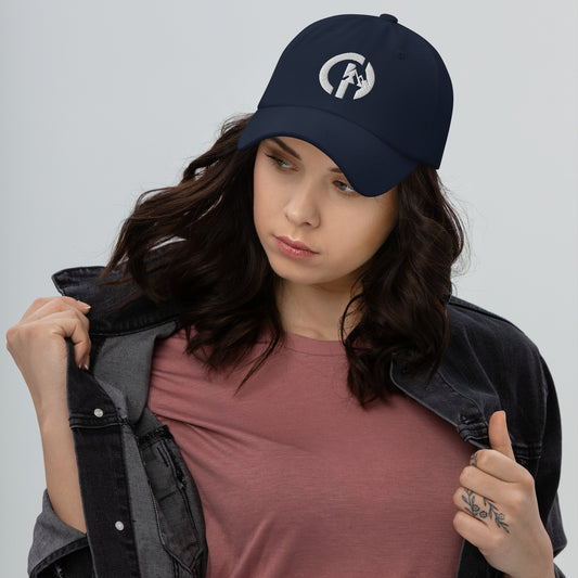 Chillhawk Classic Dad Cap Navy - a person with light skin and long, wavy brown hair, is shown looking to the side while wearing a navy cap with a white circular logo on the front and a dark denim jacket over a reddish-brown shirt.