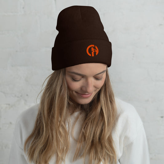 Chillhawk Limited Edition Cuffed Beanie Brown - Hypoallergenic, unisex style, hand washable - A lady with long, light-colored hair, is looking down and wearing a brown cuffed beanie with an orange circular logo on the front.